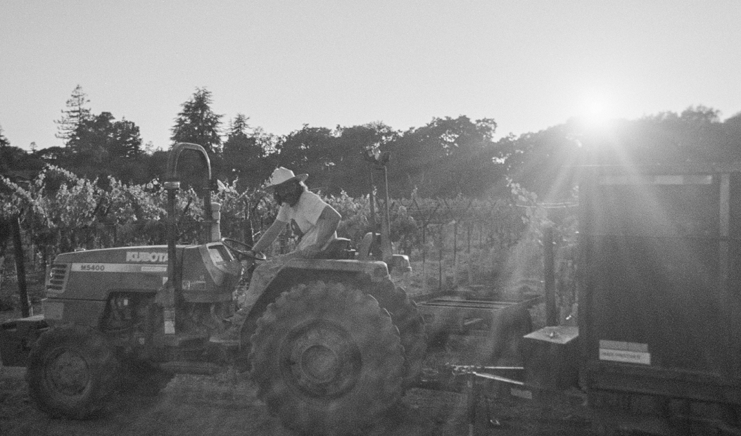 Man driving a tractor pulling a large wooden bin